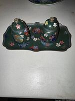 Top view of the set showing the rectangular tray and two bell-shaped cloisonné pieces with floral patterns on a dark green base.