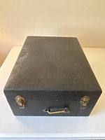 Closed black leather-covered portable case with brass latches and handle for Columbia Grafonola model 162.