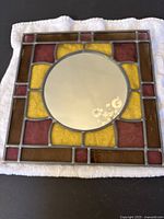 Top-down view of the entire stained glass mirror showing the colorful glass frame and round mirror center.