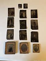 Top-down image displaying all 14 photos arranged on a table, showing a variety of portraits with some photos framed in embossed metal mats and others loose tin types.