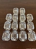Top view of fourteen clear crystal salt cellars arranged in rows, showing their intricate interior cut pattern.