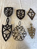 Top-down view showing all six antique iron stands laid out on a white cloth, displaying their shapes and designs