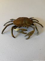 Front angle view of vintage solid brass crab trinket box showing articulated claws and patina