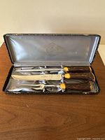 Top view of the vintage carving set showing all four pieces with faux antler Bakelite handles in original case with satin lining and King Carver branding on blades.