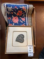 Textile art and floral cloth with framed heart embroidery and folded decorative cloth.