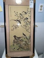 Full view of framed painting showing birds on blossoming tree branches with Asian calligraphy and red seal. Mounted on silk damask mat with black frame and brass corners.