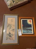 Both framed artworks displayed on floor: tall narrow Chinese silk painting and smaller Japanese woodblock print