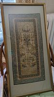 Front view of the framed embroidered textile art runner showing the full piece with visible Asian calligraphy and ornamental design elements.
