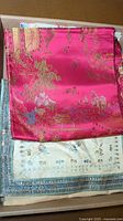 Bright pink runner with golden embroidered Asian landscape pattern and dark pink fringe seen folded.