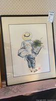 Full view of framed watercolor painting depicting person carrying plants from behind with hat and bags.