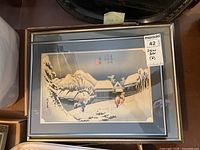 Front view of one framed print showing snowy village and travelers, with lot label visible