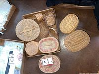 Top down view of several baskets in a cardboard box and on the floor, various sizes and shapes