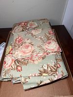 Twin bed sheets folded and stacked showing floral pattern with roses and leaves.