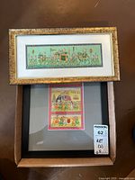 View showing both framed artworks together in box, one with gold frame, one with black frame, confirming two distinct pieces