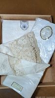 Folded linens with cream lace edged napkins in a box