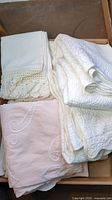 White and pink vintage pillowcases with crochet lace and embroidery detail inside a box