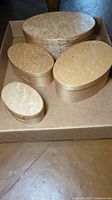 Four oval birdseye maple Shaker boxes placed inside a cardboard box showing top lid views.