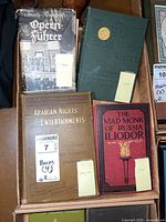 Four vintage and antique books arranged in a box, visible titles and condition shown.