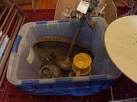 Blue plastic bin containing yellow Dietz lantern, oval wire basket, two lamp bases, and miscellaneous parts