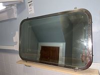 Full view of the rectangular vintage mirror showing metal frame and beveled glass.