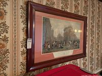 Framed vintage engraving print hanging on a patterned wallpapered wall, showing full front view of the artwork and frame.