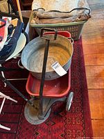 Photo showing the Radio Flyer red metal wagon with black handle and four wheels. The wagon has rust and wear.