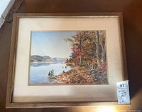 Photo of the framed watercolor painting showing the full artwork with a wooden frame and matting, highlighting the vibrant autumn lakeside scene.
