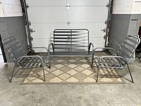 Full set of one loveseat and two matching side chairs in gray powder coated finish arranged on a patterned rug in front of a garage door.