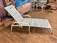 Side angled view of the beige aluminum frame chaise lounge with light blue strapping and adjustable backrest.
