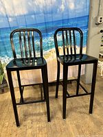 Two black aluminum modern barstools with vertical slat backs and powder-coated finish side-by-side