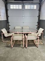 Front view of oval glass-top table with six matching sling chairs arranged around it in a garage.