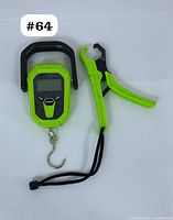 Top-down view of digital hanging scale and fish grip tool laid flat on white background with lot number sticker.