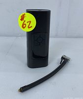 Black portable cordless air compressor device with digital display and control buttons, shown without hose attached, lying on surface.