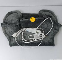 Soft dark gray heating pad folded with white electronic controller and power cord visible on top. Yellow sticker #77 attached.