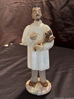Full view of the veterinarian figurine standing on marbleized base with animals in arms.