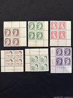 Overview photo showing six different plate blocks of early Queen Elizabeth II Canadian stamps arranged in two rows of three blocks each on a black background.