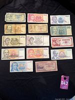 Full collection laid out on dark cloth showing various denominations and styles of Yugoslavian paper money.