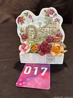 Full view of the Royal Albert garden ornament with ceramic flowers in front and scenic backdrop.