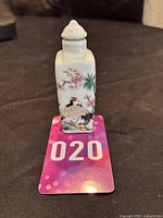 Front view showing crane and blossom design, white porcelain bottle with lid on top