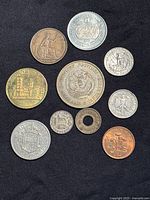 Ten coins and tokens arranged on black background