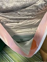 Bag showing stacked grey patterned sheets and aqua quilt at bottom