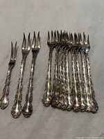 Group of ornate handled specialty forks, two size groups visible