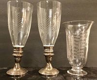 Front view of both candle holders and vase showing etched designs