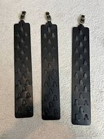 Three black leather thimble holder straps laid flat showing cut-outs