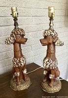 Two plaster poodle lamps without shades showing full form and sockets