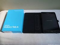 Tablet in folio beside blue Samsung Galaxy Tab A box