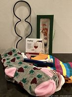 All lot items grouped: wine rack, Pulltex Drop Savers box, snowman stopper in green box, sample socks