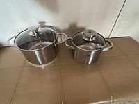 Two stainless pots with lids on surface
