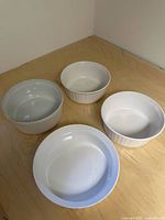 Four white ceramic bowls of different sizes on a wood surface, showing size and color