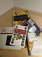 Five gardening books stacked on a wooden surface showing covers and titles